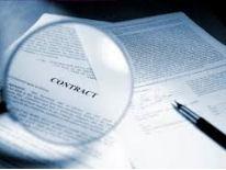 Fountain pen sitting on top of a business form document with a magnifying glass magnifying the text Contract