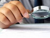 Hand holding a magnifying glass on top of a document